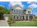 Two-story home showing board and batten, stone accents, large windows, and a well-manicured lawn with landscape at Tbd Charlotte Knoll St # 13, Zebulon, NC 27597