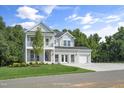 Elegant two-story home featuring a double-decker porch, a green lawn, and a roomy three-car garage at 125 Charlotte Knoll St # 15, Zebulon, NC 27597