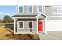 Inviting front porch with red door, white columns, and gray siding, leading to a two-car garage at 3689 Nc 62, Burlington, NC 27217
