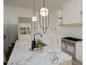Modern kitchen with white cabinets, marble countertops, and stainless steel appliances provides luxurious cooking space at 3813 Peaceful Creek Trl, Zebulon, NC 27597