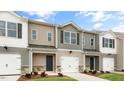 Three-unit townhome building with gray and beige siding, two-car garages, and landscaping at 422 Honeycutt Oaks Dr, Angier, NC 27501