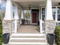 Cozy front porch with stone pillars, a bench, and a hanging lantern, perfect for relaxing at 101 Pointe Park Cir, Holly Springs, NC 27540