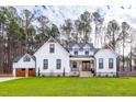 White farmhouse with brown doors, stone accents, and a manicured lawn at 257 Rawhide Dr, Louisburg, NC 27549