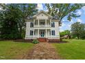 Two-story white house with blue shutters, wraparound porch, and stone pathway at 309 Hawkins Ave, Sanford, NC 27330