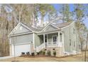 Charming one-story home featuring light green siding, a cozy front porch, and a well-manicured lawn surrounded by mature trees at 100 Sequoia Dr # 2387, Louisburg, NC 27549