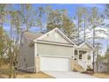 Side view of a one-story home with light green siding, attached garage, and freshly poured driveway surrounded by tall trees at 100 Sequoia Dr # 2387, Louisburg, NC 27549