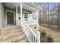 A close-up of the porch with light brick support columns, white rails, and a welcoming front door with a wreath at 100 Sequoia Dr # 2387, Louisburg, NC 27549