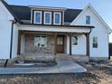 Charming new construction home featuring a brick-and-white facade and a welcoming covered porch with wooden pillars at 321 Bud Wall Rd, Youngsville, NC 27596