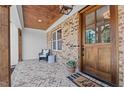 Inviting front porch with brick floor, sitting area, wood ceiling, and natural wood door at 321 Bud Wall Rd, Youngsville, NC 27596