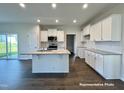 Modern kitchen with island, white cabinets, and hardwood floors at 389 Springtooth Dr, Zebulon, NC 27597