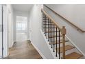 Elegant staircase featuring hardwood steps, black iron spindles, and natural wood banister at 708 Georgias Landing Pkwy # 14, Raleigh, NC 27603