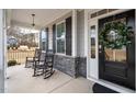 Inviting front porch with rocking chairs, black front door and stone accents at 804 Peterson Ridge Rd, Fuquay Varina, NC 27526