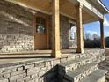 Covered porch with exposed wood beams and stone base, featuring a natural wood door and stone steps at 810 Maggie Way, Wendell, NC 27591