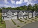 New construction townhomes featuring attached garages and modern exteriors with landscaped yards and a beautiful tree line backdrop at 8945 Kennebec Crossing Drive # 54, Angier, NC 27501