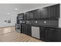 Modern kitchen featuring dark cabinetry, new appliances, and stylish backsplash at 905 Corona St, Durham, NC 27707