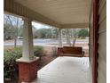 Spacious front porch with wooden swing and brick columns at 3077 Christian Light Road Rd, Fuquay Varina, NC 27526