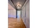 Elegant gray hallway featuring wainscoting, hardwood floors, and a view into a sunlit room at 727 Cook Rd, Durham, NC 27713