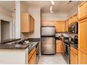Galley kitchen featuring stainless steel appliances, granite countertops and natural-toned wood cabinets at 1300 Durlain Dr # 108, Raleigh, NC 27614