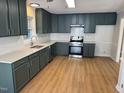 Updated kitchen with green cabinets, quartz countertops, and stainless steel appliances at 3212 Potthast Ct, Raleigh, NC 27616