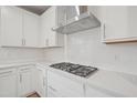 Close up of the gas range and ventilation hood in a modern white kitchen at 4804 Cypress Tree Ln, Raleigh, NC 27612