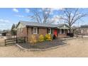Inviting brick home with metal roof, tidy landscaping and a vibrant red front door at 593 Bailey Rd, Coats, NC 27521