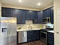 Modern kitchen features stainless steel appliances, white countertops, dark cabinets and sleek backsplash at 1211 Canyon Rock Ct # 111, Raleigh, NC 27610