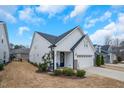 White two-story home showing manicured landscaping, a two-car garage and inviting front entrance with a dark blue door at 12408 Angel Vale Pl, Durham, NC 27703