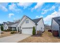 Side view of a white home featuring a two-car garage, driveway, and manicured landscaping at 12408 Angel Vale Pl, Durham, NC 27703