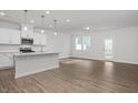 Bright, open-concept kitchen with stainless steel appliances and a large island with pendant lighting at 3860 Well Fleet Drive, Fuquay Varina, NC 27526