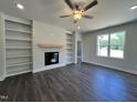 Cozy living room with a ceiling fan, fireplace, built-in shelves, and hardwood flooring at 45 Mossman Ct, Zebulon, NC 27597