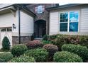 House entrance with stone accents, landscaping, and a two-car garage at 7845 Hasentree Lake Dr, Wake Forest, NC 27587