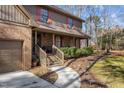Inviting home entrance with a brick facade, wooden steps, landscaped bushes, and a curved walkway at 11509 Hardwick Ct, Raleigh, NC 27614