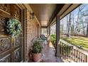 Cozy front porch featuring tiled flooring, comfortable seating, brick columns, and a decorated door at 11509 Hardwick Ct, Raleigh, NC 27614