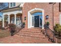 Elegant red brick home entrance with a black front door, white trim, and manicured landscaping at 2035 Stuart Ct, Burlington, NC 27215