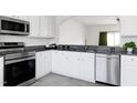 Bright kitchen features stainless steel appliances, granite countertops, white cabinets, and gray tile floor at 307 Walnut Woods Dr, Morrisville, NC 27560