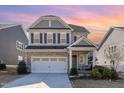 Two-story home with gray siding, stone accents, and a two-car garage at sunset at 328 Golf Vista Trl, Holly Springs, NC 27540