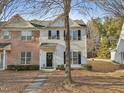 Two-story townhome with brick and white paneled siding, black shutters, and a welcoming front door at 5809 Neuse Wood Dr, Raleigh, NC 27616