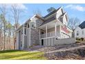 Side view of a two story home with stone and gray siding, deck, and wooded lot at 5920 Orchid Valley Rd, Raleigh, NC 27613