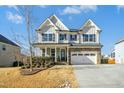 Two-story house with stone and shingle accents, a three-car garage, and manicured landscaping at 6324 Fauvette Ln, Holly Springs, NC 27540