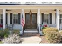 Inviting covered porch with columns, ceiling fans, and double wood doors at 1141 Barley Stone Way, Raleigh, NC 27603
