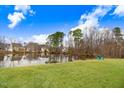 Serene backyard featuring a picturesque pond reflecting the sky, surrounded by lush green lawn and mature trees at 130 Daniel Farm Dr, Benson, NC 27504