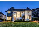Elegant white brick home with beautiful landscaping illuminated at twilight showcases classic architectural design at 1324 Brooks Ave, Raleigh, NC 27607