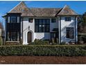 Charming white brick home boasting black window frames, and manicured landscaping, showcasing timeless curb appeal at 1324 Brooks Ave, Raleigh, NC 27607