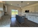 Well-lit kitchen features an island, granite countertops, sleek cabinets, and stainless steel microwave at 59 Pretty Run Branch Ln, Wendell, NC 27591