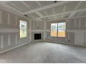 Unfinished living room featuring two windows, a fireplace, and fresh drywall at 59 Pretty Run Branch Ln, Wendell, NC 27591