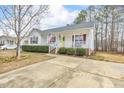 Quaint single-story home featuring a covered front porch, American flag, yellow front door, and concrete driveway at 1029 S Philwood Ct, Fuquay Varina, NC 27526