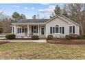 Beige house with a covered porch, landscaping, and a spacious lawn at 207 Meadowbrook Ln, Oxford, NC 27565