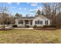 Tan house with covered porch, landscaping, and grassy yard at 207 Meadowbrook Ln, Oxford, NC 27565
