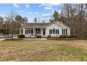 Tan house with covered porch, landscaping, and grassy yard at 207 Meadowbrook Ln, Oxford, NC 27565