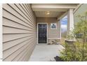 Covered front porch with stone accents and stylish black front door at 245 E Webber Ln, Clayton, NC 27527